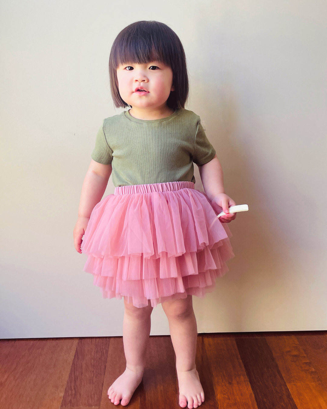 Charming toddler girl showcasing our Pale Rose Tutu Skirt. Explore comfort and style for your little one's precious moments with Dear Pastel.
